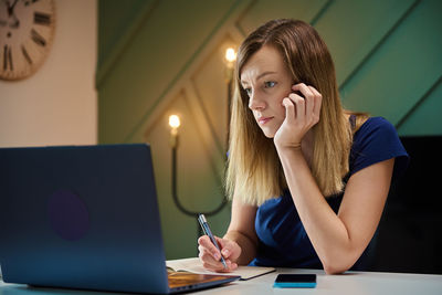 Woman working remotely from home office, using laptop