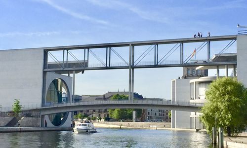 Bridge over river in city against sky