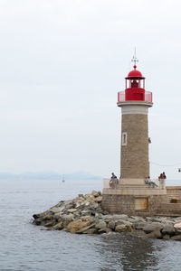 Lighthouse by sea against sky