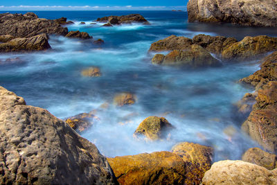 Scenic view of rocks in sea against sky