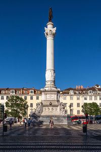 Statue in city against clear blue sky