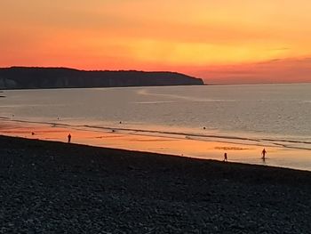 Scenic view of beach against orange sky