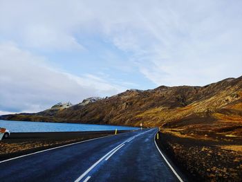 Road leading towards mountains against sky