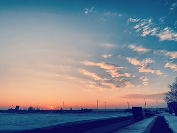 Road by sea against sky during sunset