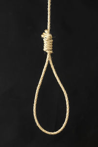 Close-up of rope tied up against black background