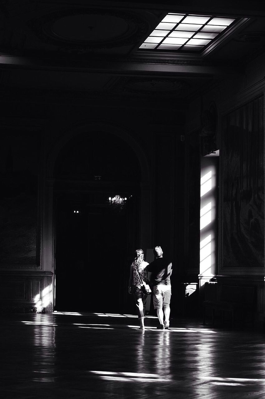 indoors, architecture, built structure, full length, door, arch, entrance, flooring, illuminated, lifestyles, window, architectural column, corridor, person, doorway, reflection, rear view, building exterior