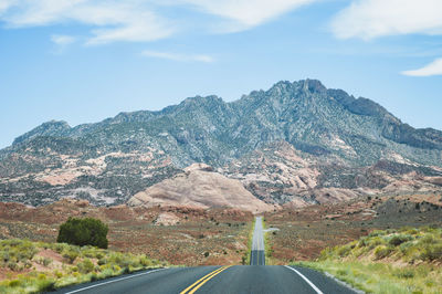Road leading towards mountains against sky
