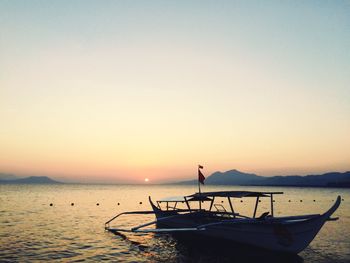 Silhouette floating on sea against sky during sunset