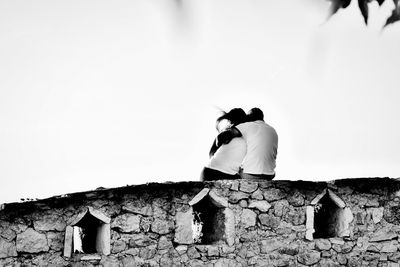 People on wall against sky