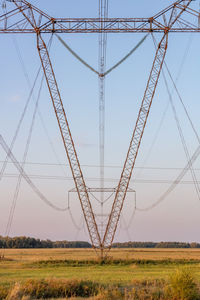 Low angle view of electricity pylon on field against sky