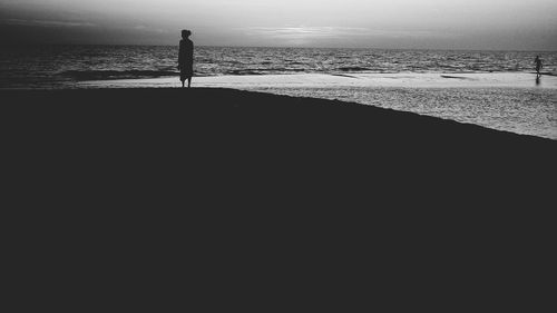 Silhouette woman standing on beach against sky