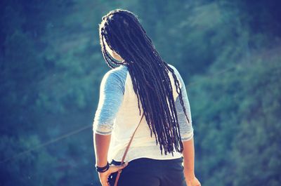 Rear view of young woman with dreadlocks standing outdoors