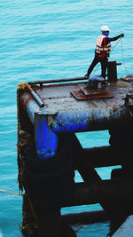 Rear view of man standing on boat at sea