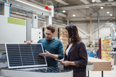 Businessman discussing with colleague over solar panel in industry