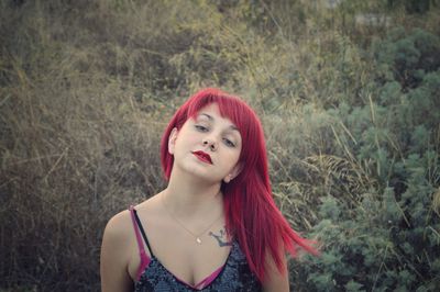 Portrait of redhead young woman against plants