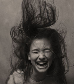 Happy woman with tousled hair against wall