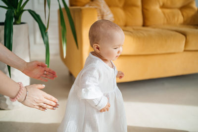 Mom's hands reach for a little daughter in white dress