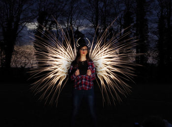 Portrait of woman standing against light painting