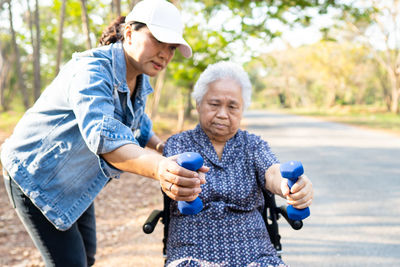 Woman assisting senior patient holding dumbbells