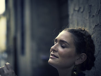 Close-up of young woman with eyes closed against wall