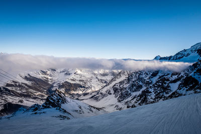 Scenic view of snow covered mountains against blue sky