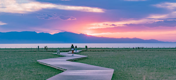 People on beach against sky during sunset