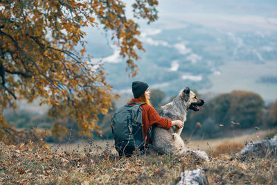 Rear view of person with dog on field during autumn