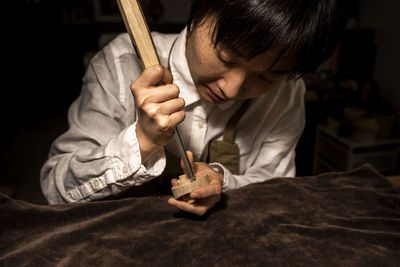 Young chinese violin maker at work in her workshop