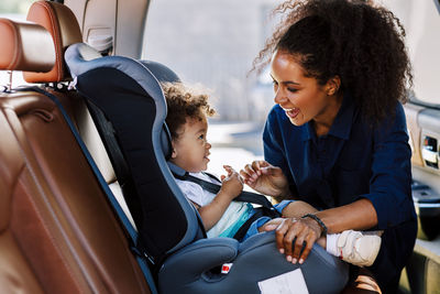 Cheerful woman with toddler son sitting in car