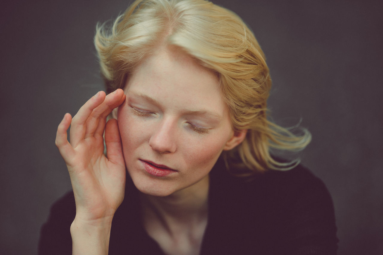 Close-up of young woman against black background