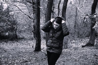 Man standing by tree trunk in forest