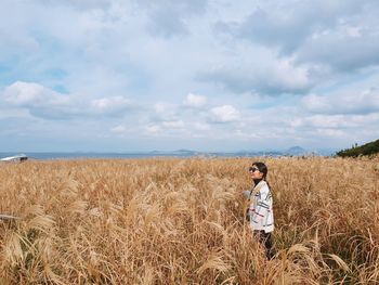 Woman standing on field against sky