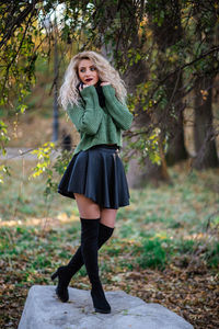 Portrait of young woman standing against tree