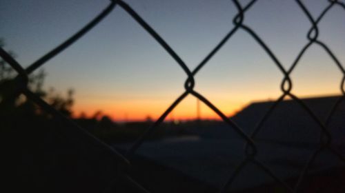 Close-up of silhouette fence against sunset sky