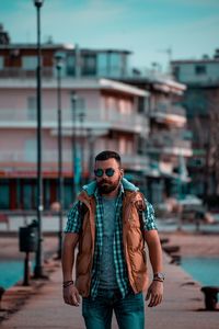 Portrait of young man standing against buildings in city