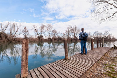 Man standing by lake against sky