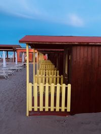 Empty chairs on beach against sky