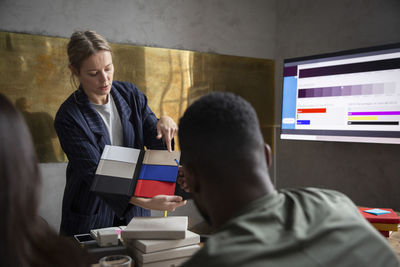 Female professional choosing colors with colleagues while discussing in office