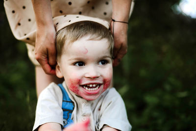 Playful son pulling mother's clothes while crouching in yard