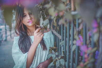 Young woman standing against flowers