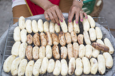 Cropped image of woman with sausages on barbecue grill