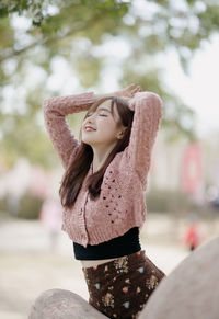 Portrait of young woman standing against trees