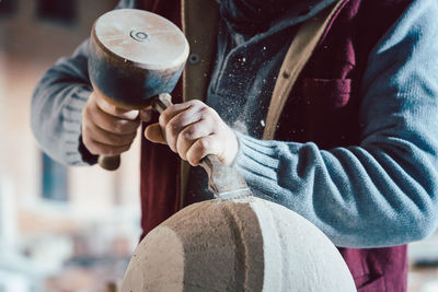 Midsection of man carving stone