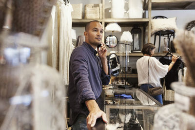 Owner taking on phone while customer looking at clothes in store