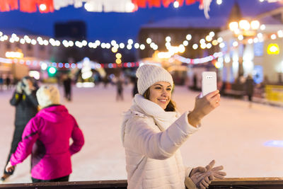 Woman standing in city at night during winter