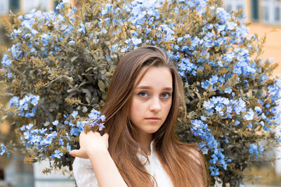 Portrait of beautiful young woman against tree