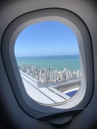 City buildings and sea seen through airplane window during takeoff 