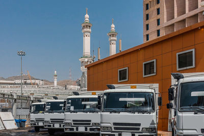 Trucks parking by building and mosque in city