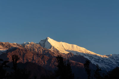 Scenic view of snowcapped mountains against clear blue sky