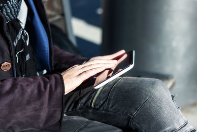 Close-up of man surfing the net on touchpad outdoors.